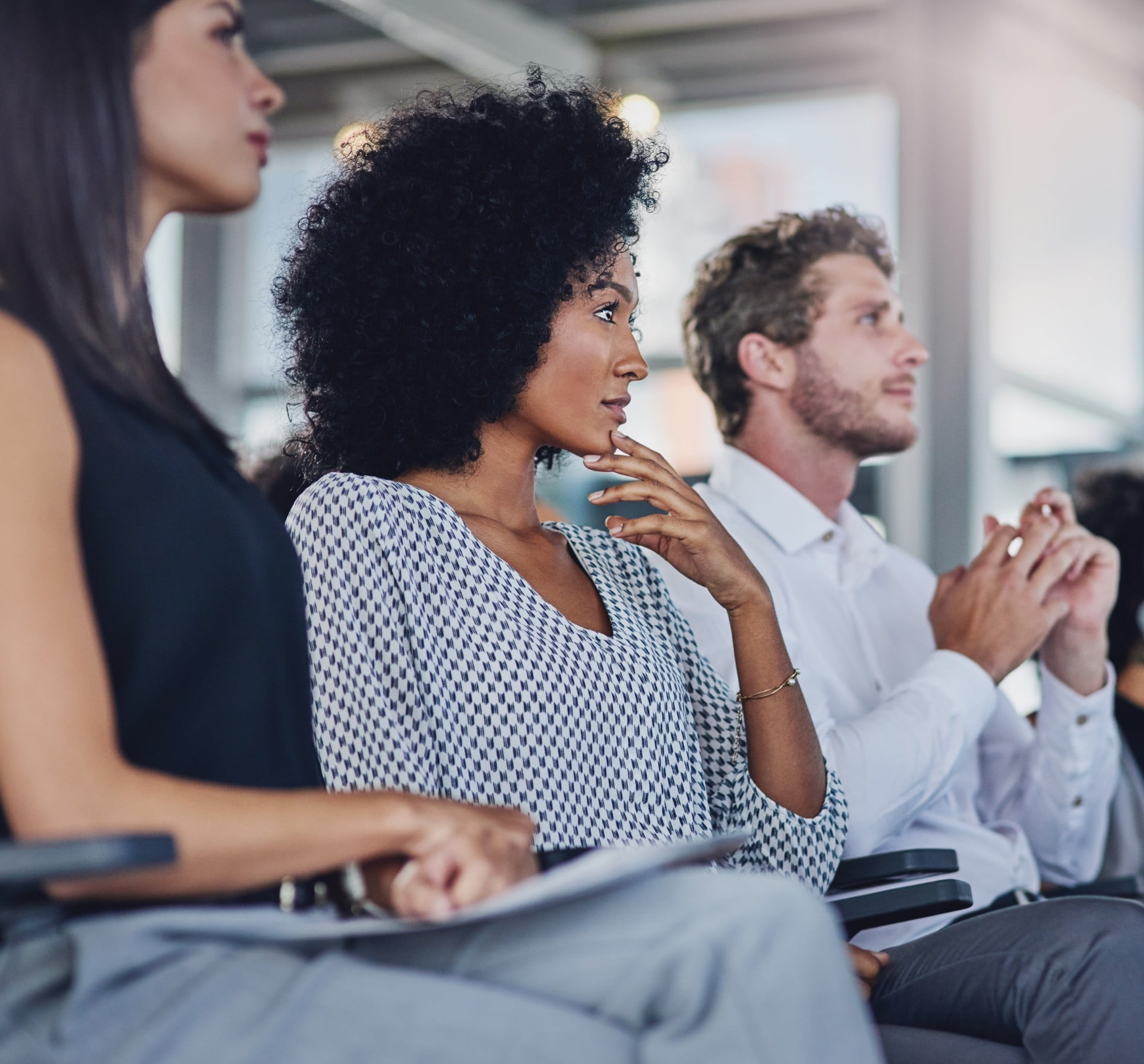 A group of people sitting in a crowd listening to a presentation